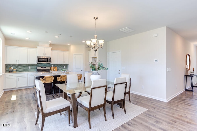 dining space with a chandelier and light wood-type flooring