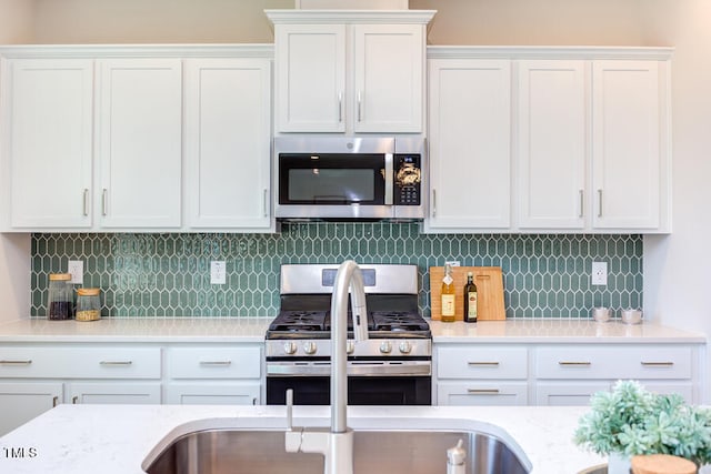 kitchen with appliances with stainless steel finishes, white cabinets, and backsplash