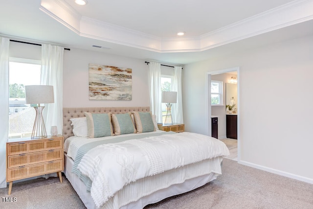 carpeted bedroom featuring a raised ceiling, crown molding, and ensuite bathroom