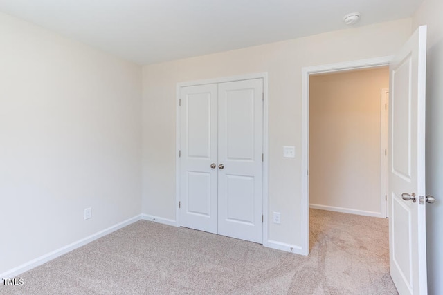 unfurnished bedroom featuring light colored carpet and a closet