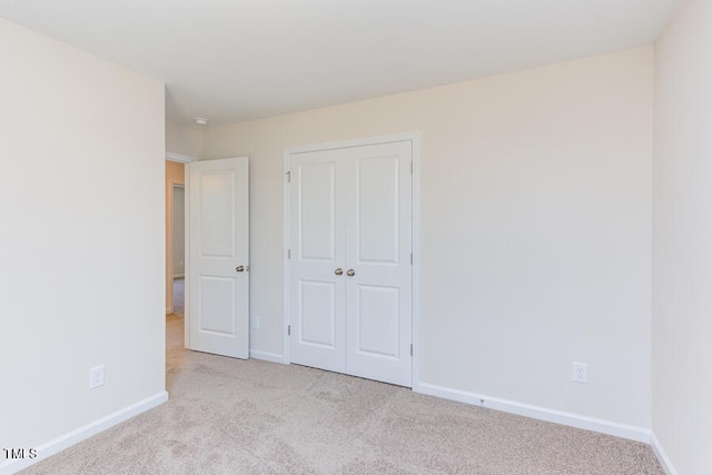 unfurnished bedroom featuring light carpet and a closet