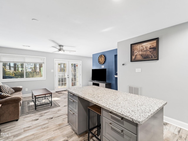 kitchen featuring gray cabinetry, light stone countertops, french doors, and light wood-type flooring