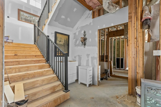 staircase featuring concrete flooring and a towering ceiling