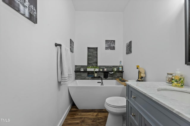 bathroom with hardwood / wood-style flooring, vanity, a washtub, and toilet