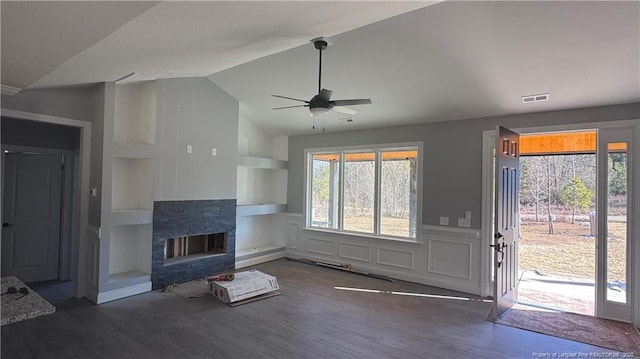 unfurnished living room featuring ceiling fan, a stone fireplace, dark hardwood / wood-style flooring, and vaulted ceiling