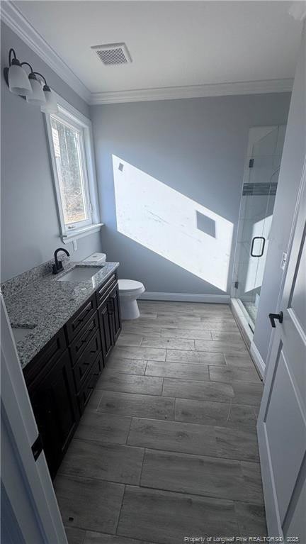 bathroom featuring walk in shower, vanity, toilet, and crown molding