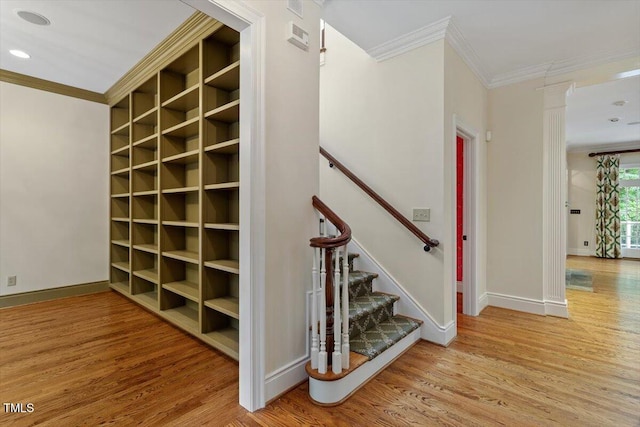 stairs with ornamental molding, wood finished floors, baseboards, and built in features