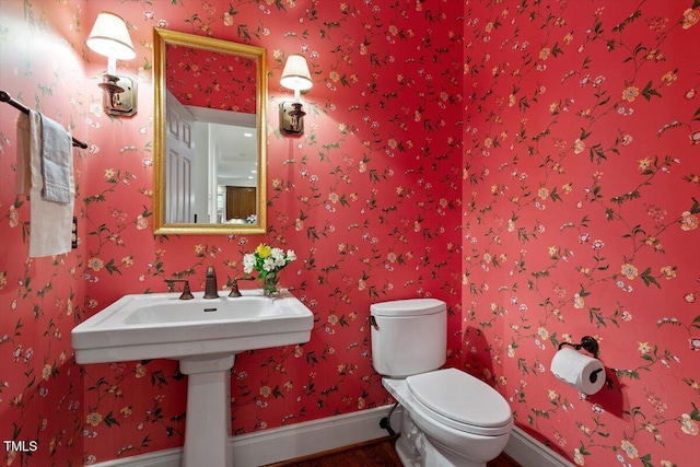 bathroom featuring toilet, baseboards, and wood finished floors