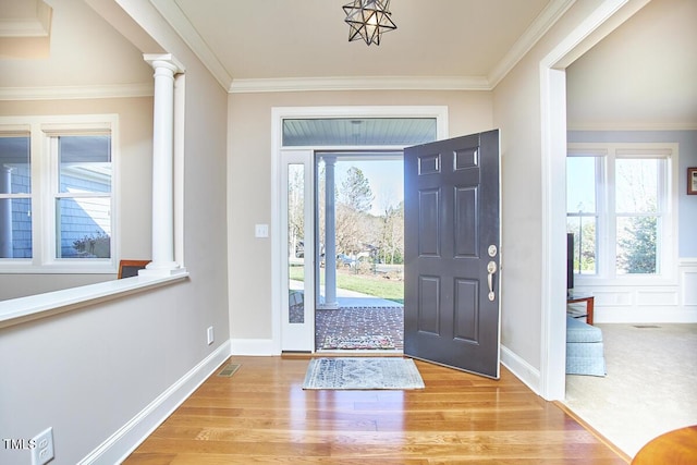 entrance foyer with crown molding, light wood-type flooring, and ornate columns