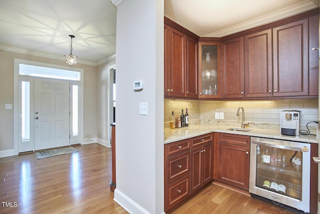 kitchen with wine cooler, sink, crown molding, light stone counters, and light wood-type flooring