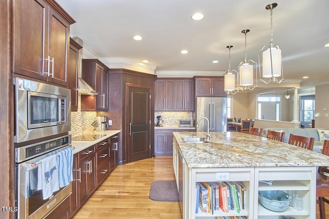 kitchen with stainless steel appliances, a breakfast bar, sink, and a center island with sink