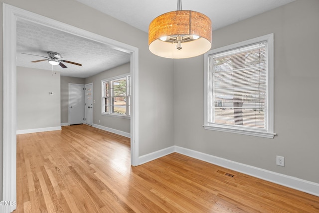 empty room with ceiling fan, a textured ceiling, and light wood-type flooring