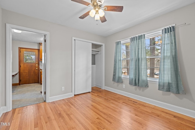 unfurnished bedroom featuring ceiling fan, a closet, and light wood-type flooring