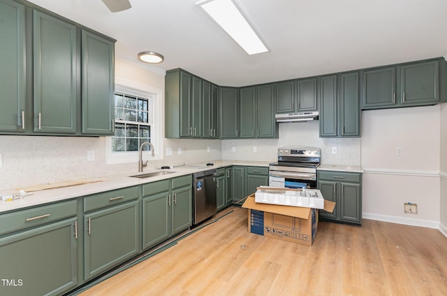 kitchen with sink, backsplash, green cabinetry, stainless steel appliances, and light hardwood / wood-style flooring