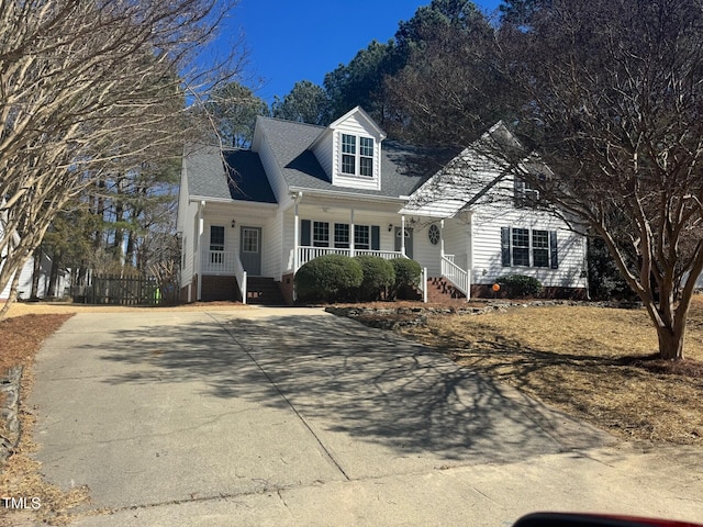 new england style home with covered porch and concrete driveway