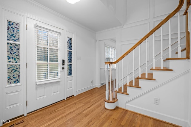 entryway featuring ornamental molding, a wealth of natural light, and light hardwood / wood-style floors