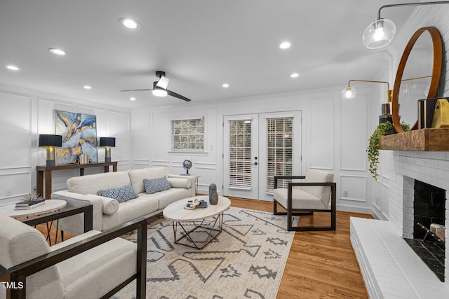 living room with french doors, crown molding, a fireplace, and light hardwood / wood-style floors