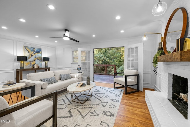 living room featuring ornamental molding, a brick fireplace, ceiling fan, and light hardwood / wood-style flooring