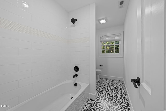 bathroom with tiled shower / bath combo, tile patterned floors, and toilet