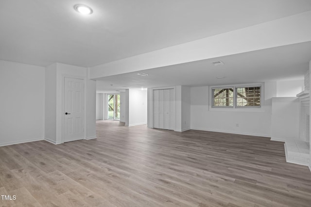 basement with a fireplace and light hardwood / wood-style floors