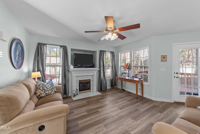 living room with a ceiling fan, wood finished floors, a high end fireplace, and baseboards