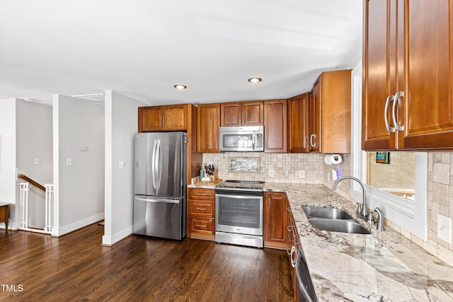 kitchen featuring dark wood-type flooring, appliances with stainless steel finishes, light stone countertops, and sink