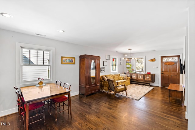 dining area featuring dark wood-type flooring and an inviting chandelier