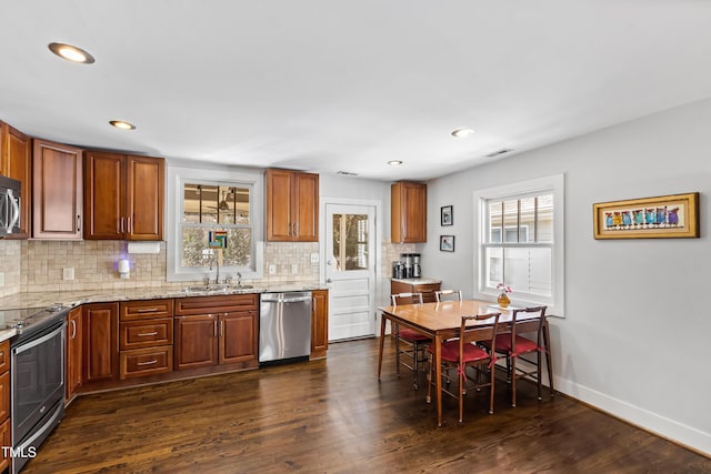 kitchen with sink, light stone counters, tasteful backsplash, dark hardwood / wood-style flooring, and stainless steel appliances