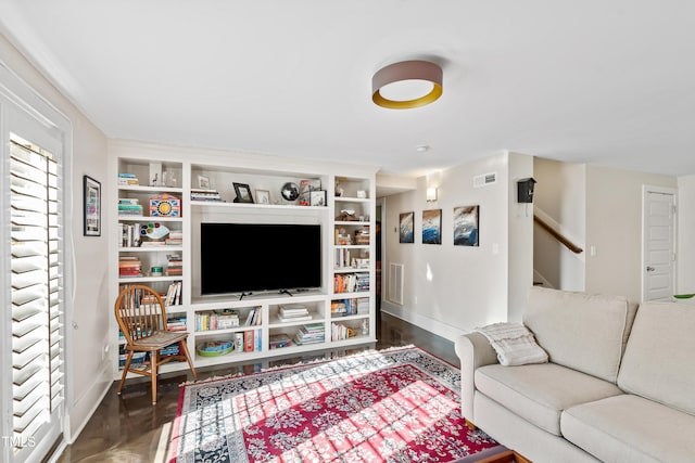 living room featuring dark wood-type flooring and built in shelves