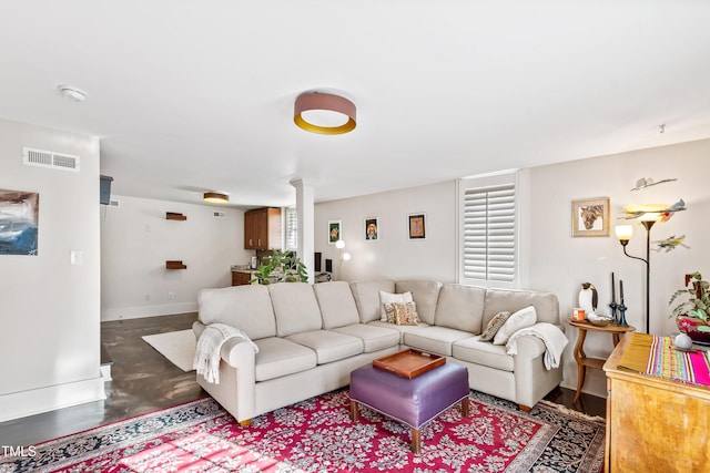 living room featuring concrete flooring and decorative columns