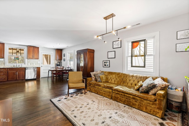 living room featuring dark wood-type flooring, plenty of natural light, a chandelier, and sink