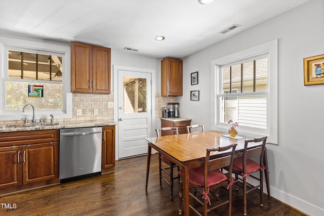 kitchen featuring sink, tasteful backsplash, dishwasher, a healthy amount of sunlight, and light stone countertops