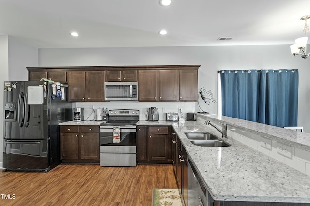 105 Langdon Chase Way, Selma, NC 27576 - kitchen with stainless steel appliances, a sink, a peninsula, dark brown cabinets, and wood finished floors