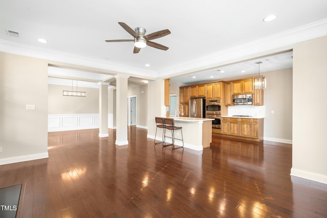 unfurnished living room featuring decorative columns, crown molding, dark hardwood / wood-style floors, and ceiling fan