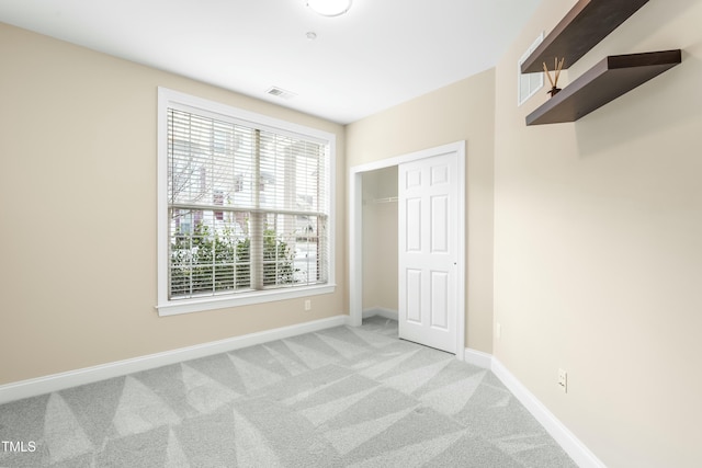 unfurnished bedroom featuring multiple windows, light carpet, and a closet