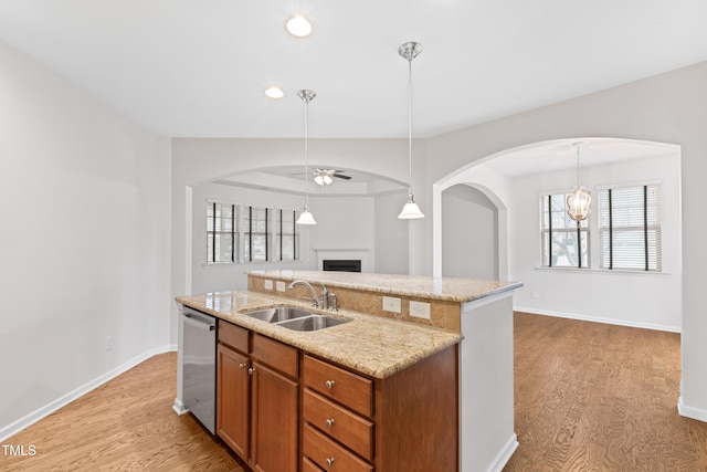 kitchen with dishwasher, sink, a kitchen island with sink, and light wood-type flooring