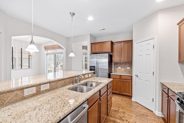 kitchen featuring light stone countertops, appliances with stainless steel finishes, sink, and decorative light fixtures