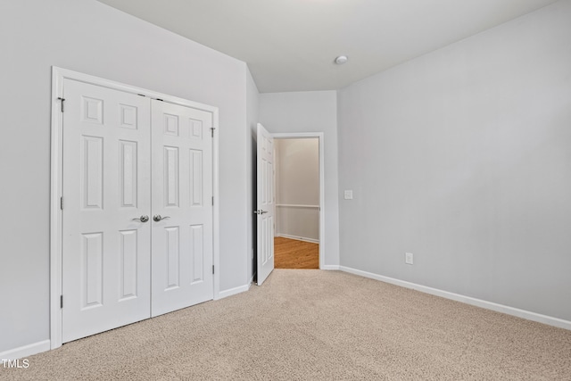 unfurnished bedroom with light carpet and a closet