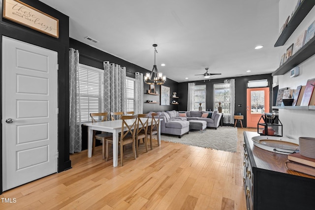 interior space with ceiling fan with notable chandelier and light wood-type flooring