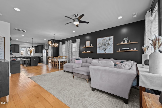 living room with hardwood / wood-style floors and ceiling fan with notable chandelier