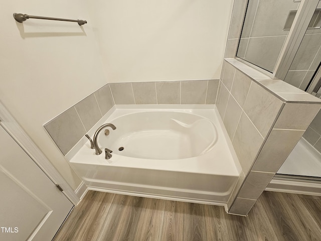 bathroom with hardwood / wood-style flooring and a tub