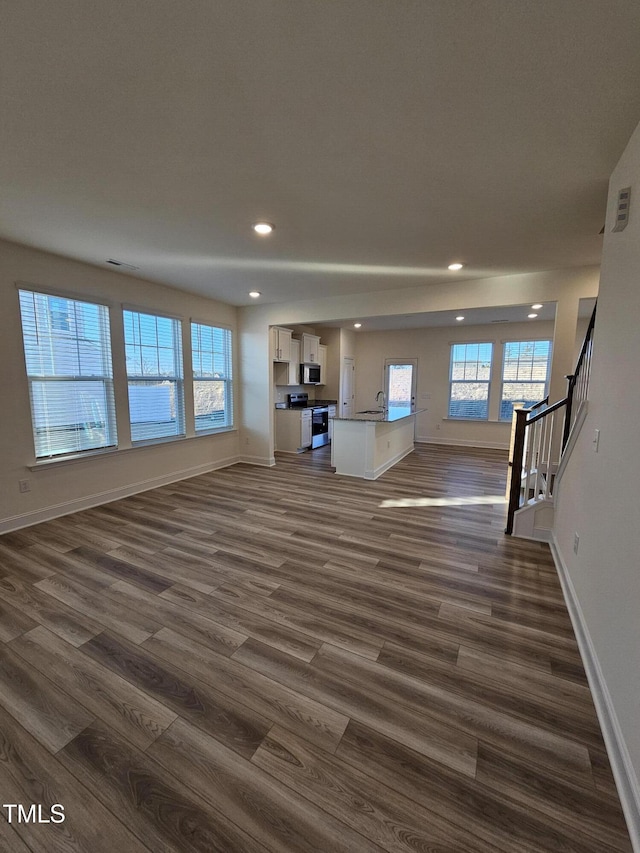 unfurnished living room featuring dark wood-type flooring and plenty of natural light