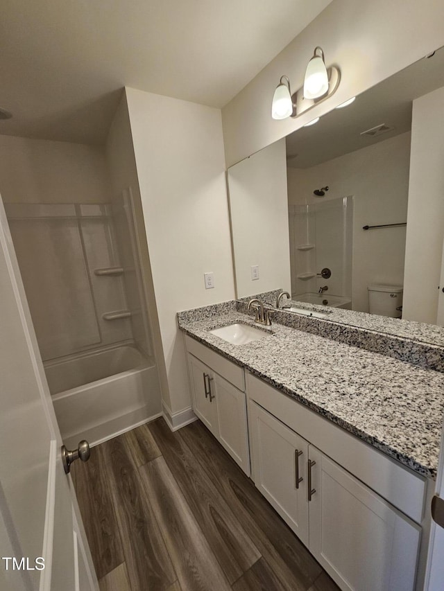 full bathroom with vanity, hardwood / wood-style flooring,  shower combination, and toilet