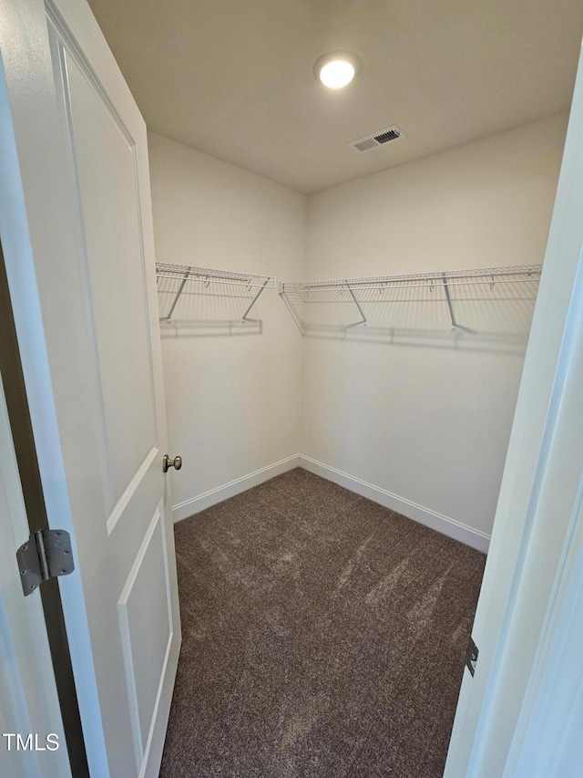 walk in closet featuring dark carpet