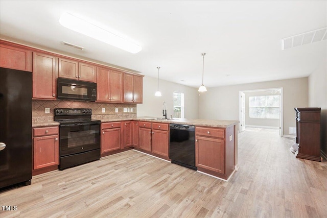 5879 Odenton Ln, Pfafftown, NC 27040 - kitchen featuring black appliances, a peninsula, a sink, and light wood-style floors