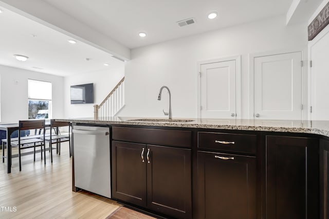 kitchen featuring sink, light hardwood / wood-style flooring, dark brown cabinetry, light stone counters, and stainless steel dishwasher