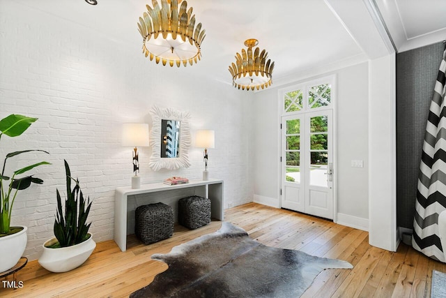 entryway featuring ornamental molding, brick wall, and light wood-type flooring