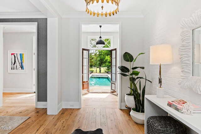 foyer entrance with crown molding, brick wall, and light hardwood / wood-style floors