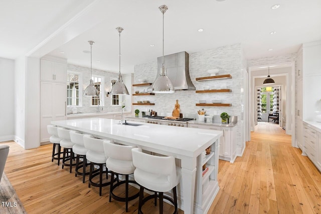 kitchen featuring sink, white cabinets, a kitchen bar, a large island with sink, and hanging light fixtures