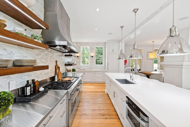 kitchen with sink, decorative light fixtures, stainless steel counters, high end stainless steel range oven, and white cabinets